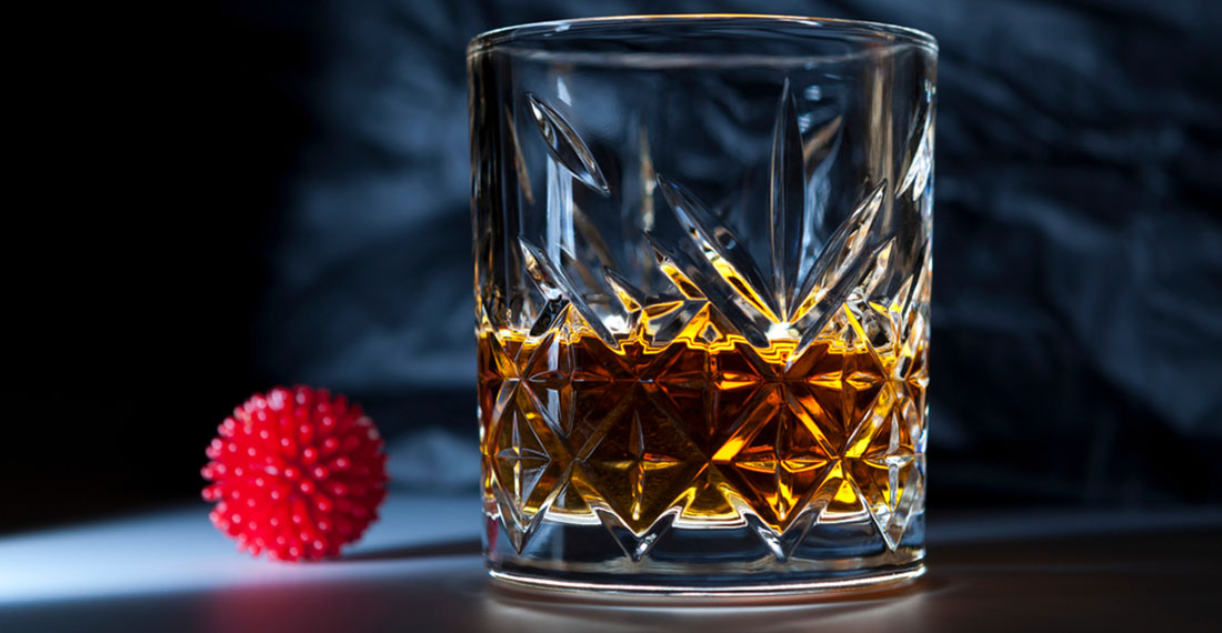 ein Glas Whisky und ein Virus-Modell