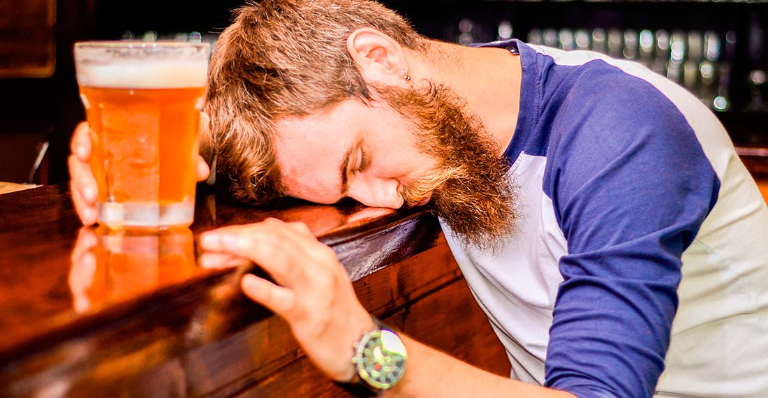 mann mit bierbecher schläft hinter der bar